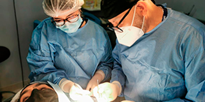 Foto de dos dermátologos realizando una intervención médica en un paciente