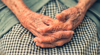 Fotografía que muestra las manos entrecruzadas de una persona mayor