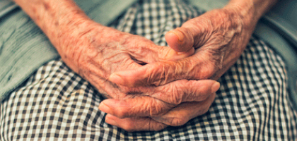 Fotografía que muestra las manos entrecruzadas de una persona mayor