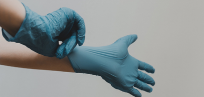 Imagen muestra las manos de profesinal de la salud colocándose guantes quirúrgicos