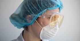 Foto que muestra el rostro de una trabajadora de la salud usando elementos de protección personal como mascarillas y gafas antisalpicaduras