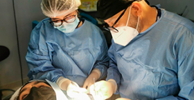 Foto que muestra a dos dermatologos realizando una intervencion quirurgica